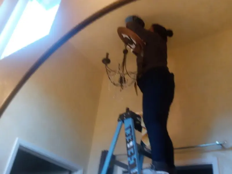 Electrician installing a chandelier in a Roosevelt Park residence
